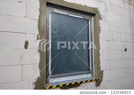 Window of a house under construction covered with protective plastic film. 132546853