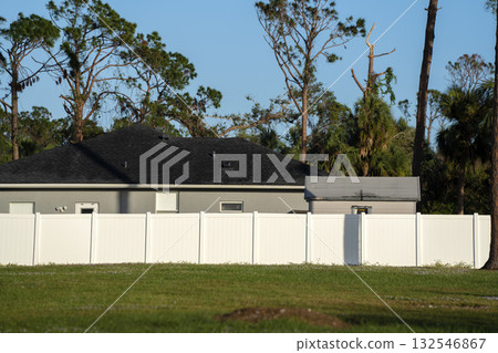 White vinyl picket fence on green lawn surrounding property grounds for backyard protection and privacy 132546867