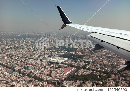 View on Mexico city through airplane window of commercial jet plane landing in local airport. Air travelling concept View on Mexico city through airplane window of commercial jet plane landing in local airport. Air travelling concept 132546890