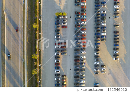 View from above of dealers outdoor parking lot with many brand new cars in stock for sale on highway side. Concept of development of american automotive industry View from above of dealers outdoor parking lot with many brand new cars in stock for sale on highway side. Concept of development of american automotive industry 132546910