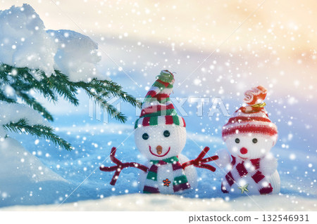 Two small funny toys baby snowman in knitted hats and scarves in deep snow outdoors on bright blue and white copy space background. Happy New Year and Merry Christmas greeting card. Two small funny toys baby snowman in knitted hats and scarves in deep snow outdoors on bright blue and white copy space background. Happy New Year and Merry Christmas greeting card. 132546931