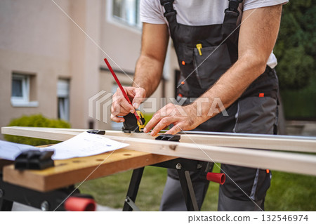 Unrecognizable men measuring wooden plank outdoors 132546974
