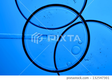 The texture of the serum with PDRN in a petri dish on a blue background. The texture of the serum with PDRN in a petri dish on a blue background. 132547301