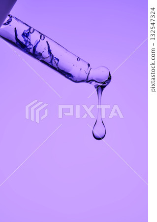 A pipette with serum demonstrating its juicy texture on a purple background. A pipette with serum demonstrating its juicy texture on a purple background. 132547324