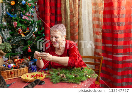Happy Senior old woman crafting. Make Christmas tree wreath. Home decoration in December DIY 132547737