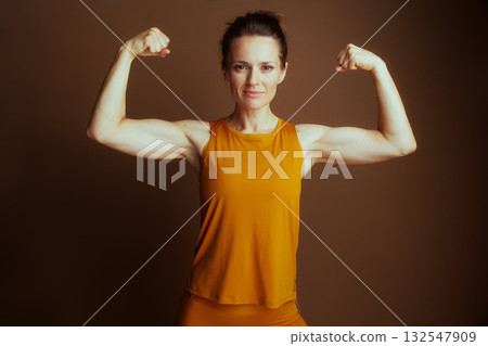 Confident Woman Flexing Biceps in Yellow 132547909