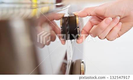 Laundry. Close-up of the dryer or washing machine control panel, a woman's hand selects the wash program. Household chores concept. 132547917