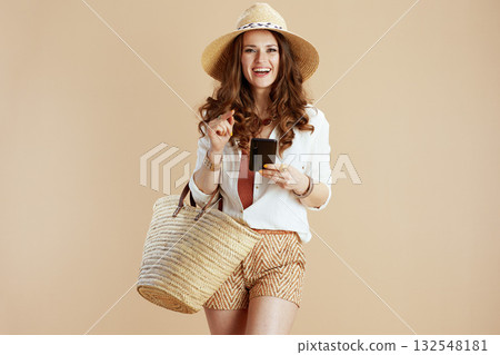 smiling woman in blouse and shorts against beige 132548181
