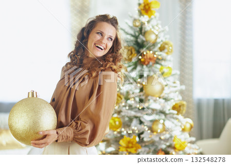 Cheerful Woman Decorates Flocked Christmas Tree Cheerful Woman Decorates Flocked Christmas Tree 132548278