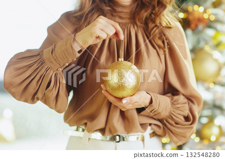 Woman\'s Hands with a Sparkling Gold Christmas Ornament 132548280