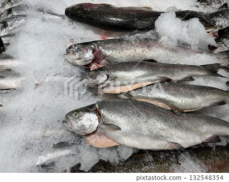 Fresh fish displayed on ice in a market setting, showcasing various species with glistening scales and a cold, frosty environment, emphasizing freshness and quality of seafood Fresh fish displayed on ice in a market setting, showcasing various species with glistening scales and a cold, frosty environment, emphasizing freshness and quality of seafood 132548354
