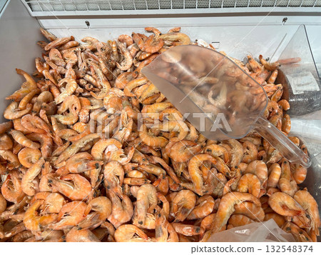 Freshly caught shrimp piled high in a seafood display, showcasing vibrant colors and textures, with a clear scoop resting on top for easy serving and selection 132548374