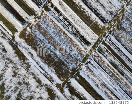 Top view of empty snowy and dark fields patched landscape on sunny winter day. Aerial drone photography concept. 132548375