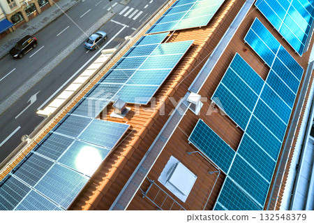 Top view of blue solar photo voltaic panels system on high apartment building roof top on sunny day. Renewable ecological green energy production concept. Top view of blue solar photo voltaic panels system on high apartment building roof top on sunny day. Renewable ecological green energy production concept. 132548379