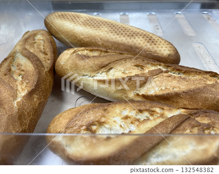 Freshly baked artisan bread loaves displayed in a transparent container, showcasing various textures and shapes, highlighting the craftsmanship of traditional baking methods 132548382
