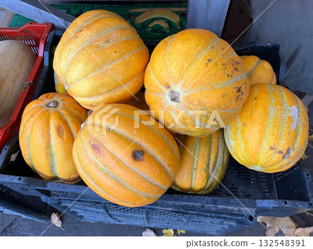 Vibrant orange pumpkins with distinctive stripes are piled together in a black crate, showcasing their natural textures and colors in a rustic market setting Vibrant orange pumpkins with distinctive stripes are piled together in a black crate, showcasing their natural textures and colors in a rustic market setting 132548391