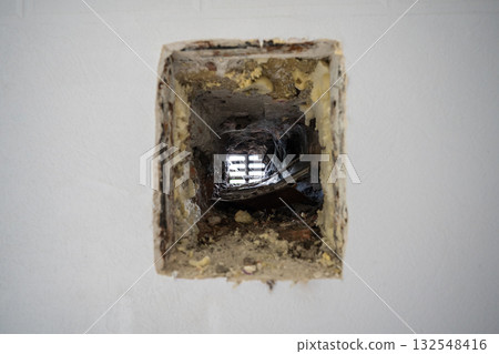 Closeup of neglected old ventilation hole in the wall of a house, covered with dust and cobwebs 132548416