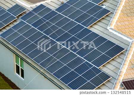 Solar panels on residential house rooftop. Photovoltaic sells for producing of clean electrical energy in suburban rural area. Concept of investment in autonomous home Solar panels on residential house rooftop. Photovoltaic sells for producing of clean electrical energy in suburban rural area. Concept of investment in autonomous home 132548515