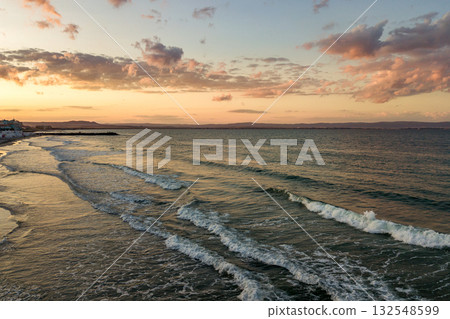 Sea surface with blue water waves under yellow and purple sunset sky. 132548599