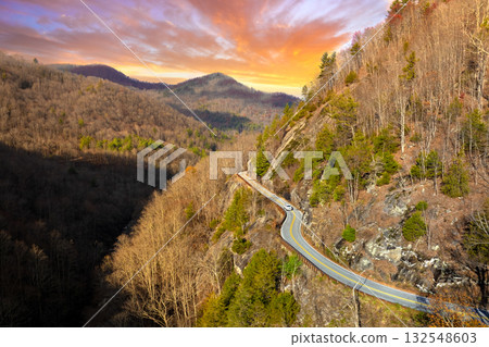 Scenic mountain road in North Carolina Highlands region. Car navigates curves beneath golden trees and steep rocky slopes in fall season. Scenic mountain road in North Carolina Highlands region. Car navigates curves beneath golden trees and steep rocky slopes in fall season. 132548603