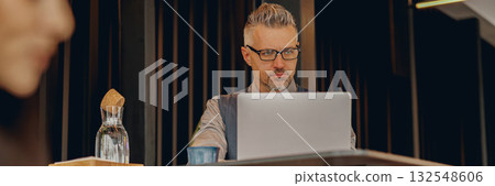 A Focused Professional Engaged in Work on a Laptop within a Modern and Stylish Workspace 132548606