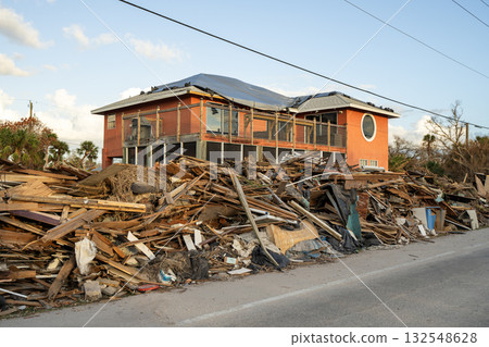 Rubbish and scrap disposed in heaps on street side after hurricane severely damaged houses in Florida home residential area. Consequences of natural disaster 132548628