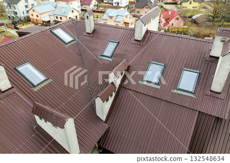 Roof of a house made from metal sheets with attic windows. 132548634