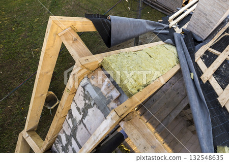 Roof construction and insulation with mineral wool. Wooden beams frame on walls of hollow foam insulation blocks. Roofing underlayment, water-resistant waterproof barrier material as protection. 132548635