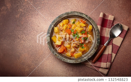 Chicken stew or soup with potatoes and carrots served in rustic bowl with spoon top view on dark brown concrete background, space for text Chicken stew or soup with potatoes and carrots served in rustic bowl with spoon top view on dark brown concrete background, space for text 132548823