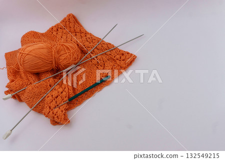 Orange cotton knit fabric with yarn and knitting tools, flat lay on light background with copy space for craft tutorials and social media content 132549215