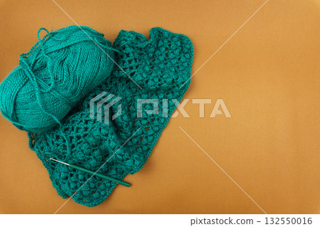 Teal crocheted item made with merino wool yarn and crochet hook on warm background, flat lay with copy space for craft tutorials and knitting inspiration Teal crocheted item made with merino wool yarn and crochet hook on warm background, flat lay with copy space for craft tutorials and knitting inspiration 132550016