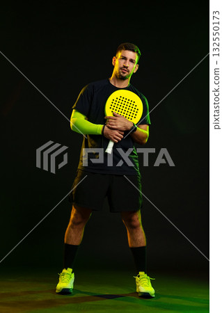Man poses with a paddle in a dramatic lighting setup during a sports session 132550173
