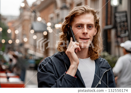 Young man talking on the phone in a vibrant city street filled with lights Young man talking on the phone in a vibrant city street filled with lights 132550174