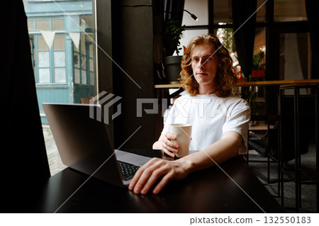 Young person working on laptop in a cozy cafe during daytime Young person working on laptop in a cozy cafe during daytime 132550183