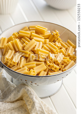 Cinque buchi. Uncooked italian pasta in colander on white table. Cinque buchi. Uncooked italian pasta in colander on white table. 132550233