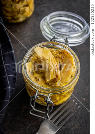 Pickled artichoke in jar on black table. 132550239
