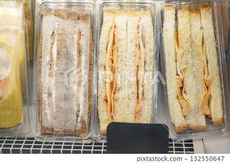 Sandwiches displayed on a shelf in a market with various fillings and bread types Sandwiches displayed on a shelf in a market with various fillings and bread types 132550647