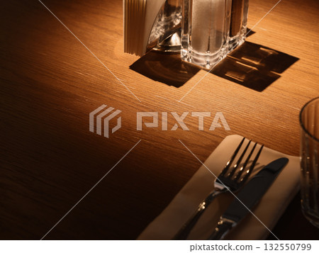 An Elegant Dining Setup Featuring Beautiful Glasses and Stylish Cutlery Laid on a Wooden Table An Elegant Dining Setup Featuring Beautiful Glasses and Stylish Cutlery Laid on a Wooden Table 132550799