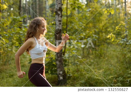 An Energetic Woman Running in a Vibrant Natural Forest Setting While Embracing Nature 132550827