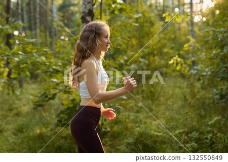 A person jogging energetically in a lush green forest during the beautiful golden hour 132550849