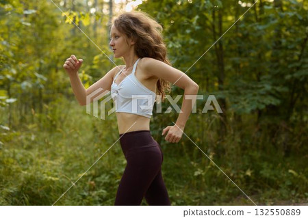 A Woman Running Through Nature Embodying Fitness, Energy, and Vitality in Motion, 132550889