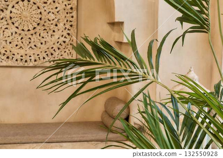 Sunlit Boho Interior with Carved Wall Decor and Tropical Palm - Serene Minimal Spa Setting Sunlit Boho Interior with Carved Wall Decor and Tropical Palm - Serene Minimal Spa Setting 132550928