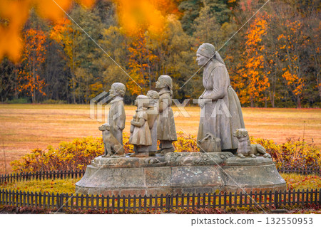 A touching statue of a grandmother and her grandchildren stands in Granny Valley, Ratiborice, Czechia. The scene is framed by colorful autumn leaves, capturing a moment of love and nostalgia. A touching statue of a grandmother and her grandchildren stands in Granny Valley, Ratiborice, Czechia. The scene is framed by colorful autumn leaves, capturing a moment of love and nostalgia. 132550953