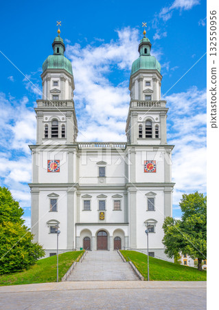 St. Lorenz Basilica, a stunning baroque structure in Kempten, Bavaria, showcases its grandeur with ornate towers and vibrant designs against a bright blue sky. St. Lorenz Basilica, a stunning baroque structure in Kempten, Bavaria, showcases its grandeur with ornate towers and vibrant designs against a bright blue sky. 132550956
