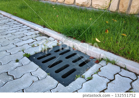 Plastic drain gutter, green grass lawn and stone pavement sidewalk. Plastic drain gutter, green grass lawn and stone pavement sidewalk. 132551752