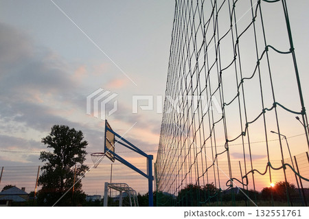 Outdoors mini football and basketball court with ball gate and basket surrounded with high protective fence. Outdoors mini football and basketball court with ball gate and basket surrounded with high protective fence. 132551761