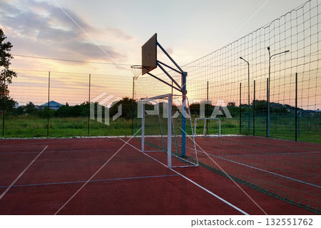 Outdoors mini football and basketball court with ball gate and basket surrounded with high protective fence. Outdoors mini football and basketball court with ball gate and basket surrounded with high protective fence. 132551762