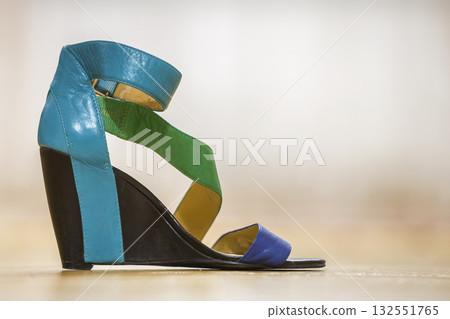 One colorful bright blue, green and yellow leather strap female shoe sandal on high black platform isolated on light copy space background. Style and fashion, modern comfortable footwear for summer. One colorful bright blue, green and yellow leather strap female shoe sandal on high black platform isolated on light copy space background. Style and fashion, modern comfortable footwear for summer. 132551765