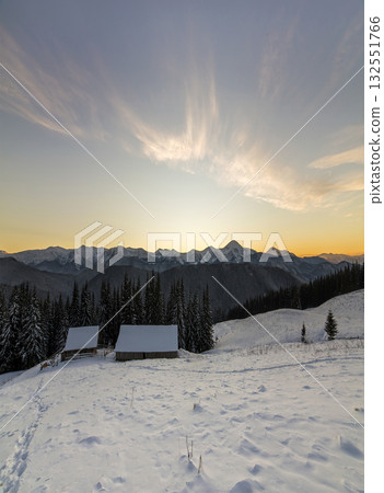 Old wooden house, hut and barn in deep snow on mountain valley, spruce forest, woody hills on clear blue sky at sunrise copy space background. Mountain winter panorama landscape. Old wooden house, hut and barn in deep snow on mountain valley, spruce forest, woody hills on clear blue sky at sunrise copy space background. Mountain winter panorama landscape. 132551766