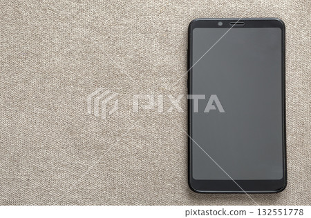 New black modern cellphone isolated on light cloth copy space background. Modern technology, communication and gadget design concept. New black modern cellphone isolated on light cloth copy space background. Modern technology, communication and gadget design concept. 132551778